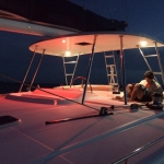Person working on a boat deck at dusk with warm overhead lights.