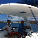Two men relaxing on a boat with a scenic ocean backdrop.