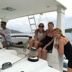 Three women relaxing on a boat under a shaded canopy.