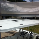White boat deck with steering console and protective cover partially removed.