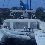 Catamaran docked by the shore with flags and equipment on board.