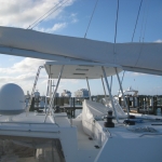 View from a yacht deck under a blue sky with city buildings in the background.