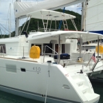 White catamaran docked with yellow fuel container on deck.
