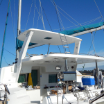 Modern white catamaran docked with clear blue sky above.