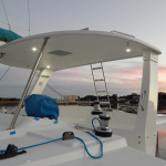 Modern boat deck with canopy and equipment at sunset.