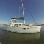 A white sailboat anchored on calm water under a clear sky.
