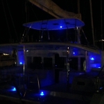 A boat illuminated with blue lights at night.