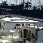 A white catamaran docked at a marina under a blue sky.