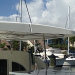 A white yacht docked at a marina under a partly cloudy sky.