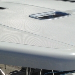 Close-up of a sleek white boat deck with a small hatch window.
