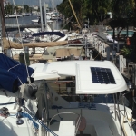 Boat docked at marina with solar panel on canopy.