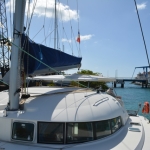 Sailboat docked in a sunny marina with clear blue skies.