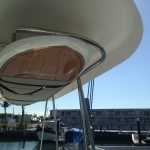 Boat canopy with rolled-up canvas under a clear sky at a marina.