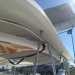 Close-up of a boat's sleek white canopy and metal support frame under a clear blue sky.
