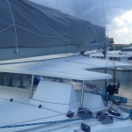 A sailboat deck with a folded sail and covered equipment.