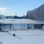 View from a yacht deck looking towards a marina with boats and cranes.