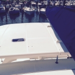 White yacht deck with blue canvas cover docked at marina.