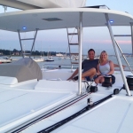Couple sitting on the deck of a white yacht on a calm day.