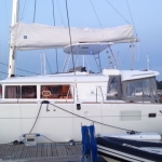 A white catamaran docked at a marina under a clear sky.
