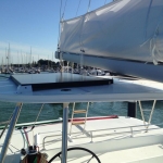 Sailboat deck with a clear blue sky and marina in the background.
