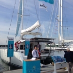 A sailboat docked with people preparing to board under a clear sky.