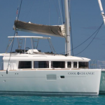 White sailing catamaran named Cool Change on calm blue water.