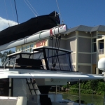A sailboat docked near residential buildings under a clear sky.