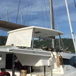 A white catamaran docked at a marina on a sunny day.