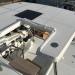 Boat cockpit with steering wheel and seating area on a sunny day.