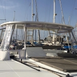 A yacht's cockpit with seating and a canopy at a marina.