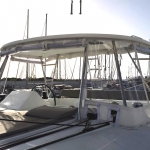 Sailboat deck with rigging and canopy under a clear sky.