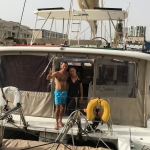 Two boys on a boat, one pointing at the camera.
