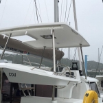 Modern catamaran docked with a covered cockpit area and visible rigging.