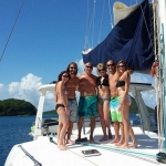 Group of friends posing on a yacht under clear blue skies.