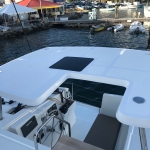Modern white boat deck with seating and control panels under a sunny sky.
