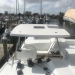White boat docked at a marina under a cloudy sky.