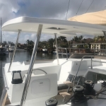View from a boat deck with steering and seating areas under a cloudy sky.