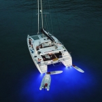 A white sailboat with blue underwater lights at night.