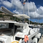 A white luxury catamaran docked at a marina under a partly cloudy sky.