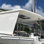 Modern sailboat with a shaded cockpit under a clear blue sky.