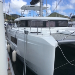 A sleek white catamaran docked at a marina on a sunny day.