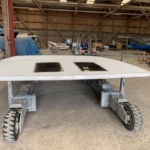 A white vehicle roof with two sunroofs in a workshop.