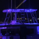 A boat illuminated with blue and purple lights at night.