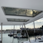 View of boats through a yacht's sunroof at sunset in a marina.