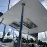 View of a boat's overhead canopy with a transparent hatch and supporting pole under blue sky.