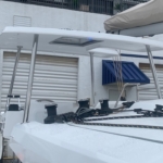 Boat deck with winches and a white canopy under a clear sky.