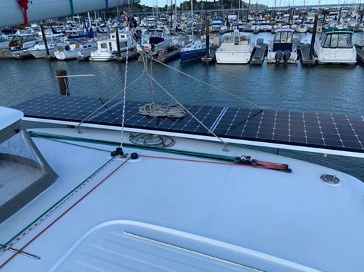 Sailboat deck with solar panels and marina in the background.