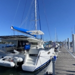 A white catamaran docked at a marina under a clear blue sky.