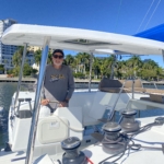 Person steering a sailboat on a sunny day.