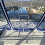 Sunlit boat deck with seating and blue trim under a clear sky.